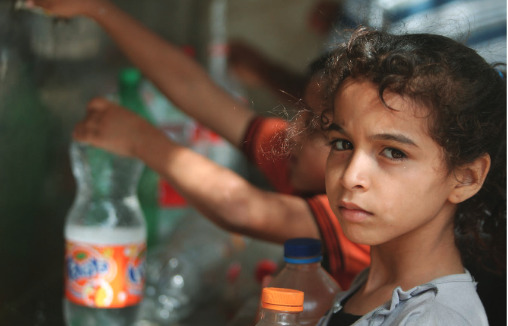 Children in Rafah collect water from one of the working public taps. Unaltered image licensed through Creative Commons. Credit: Mohammed Al Baba/Oxfam