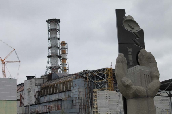Chernobyl memorial to the nuclear disaster, with reactor in the background. Credit: Ben Willis.