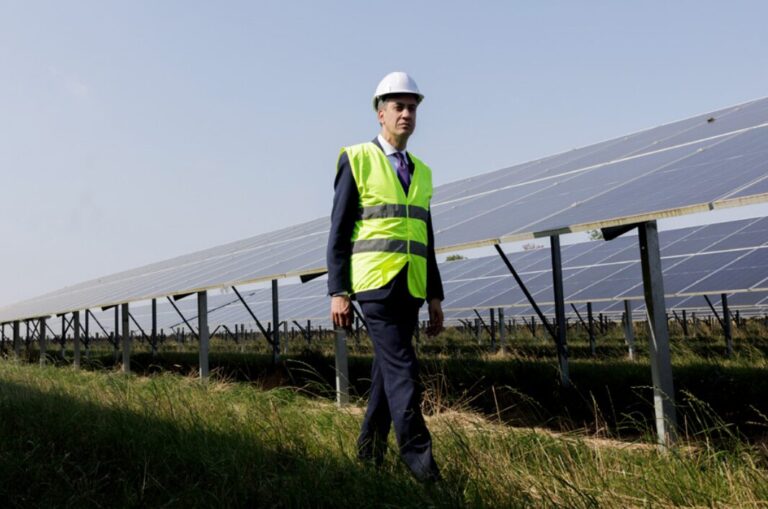 Ed Miliband walks in front of solar panels.